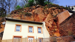 A building with three windows, a sloped roof, and a stone wall. - FELSENHAUS with view over Trier - living in the rock (Trier)
