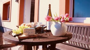 A wooden table with a bottle of wine, a glass, a vase with pink tulips, cheese, and grapes on a balcony. - FELSENHAUS with view over Trier - living in the rock (Trier)