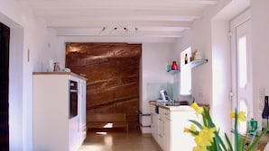 A modern kitchen with white cabinetry, a marble backsplash, and a wooden floor. - FELSENHAUS with view over Trier - living in the rock (Trier)