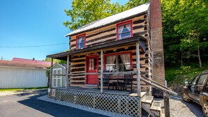 A log cabin with a porch, two red doors, and a chimney. - Stay in a 200 Year Old Log Cabin with Modern Conveniences (Bland)