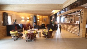 Un interior de madera con mostrador de recepción, zona de estar y chimenea.