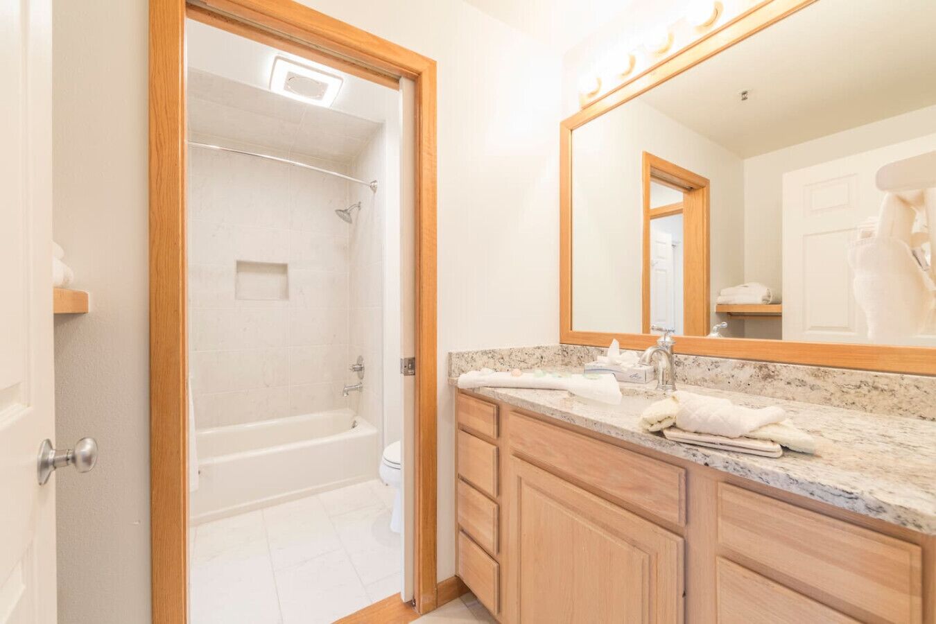 A bathroom with a shower, a sink with a mirror, and wooden cabinets.