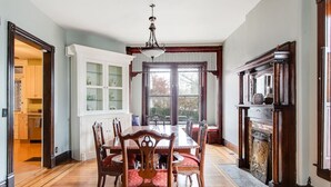 A dining room with a wooden table and chairs, a chandelier, and a fireplace. - Beautiful Victorian Louisville Home (Louisville)