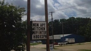 A sign for Budget Inn with a smaller sign below advertising new amenities like an APT kitchen, WiFi, and HBO ESPN.