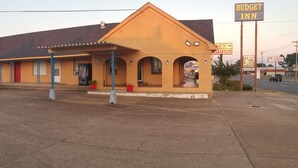 A motel with a single-story structure, a covered parking area, and a sign for 'Budget Inn'.