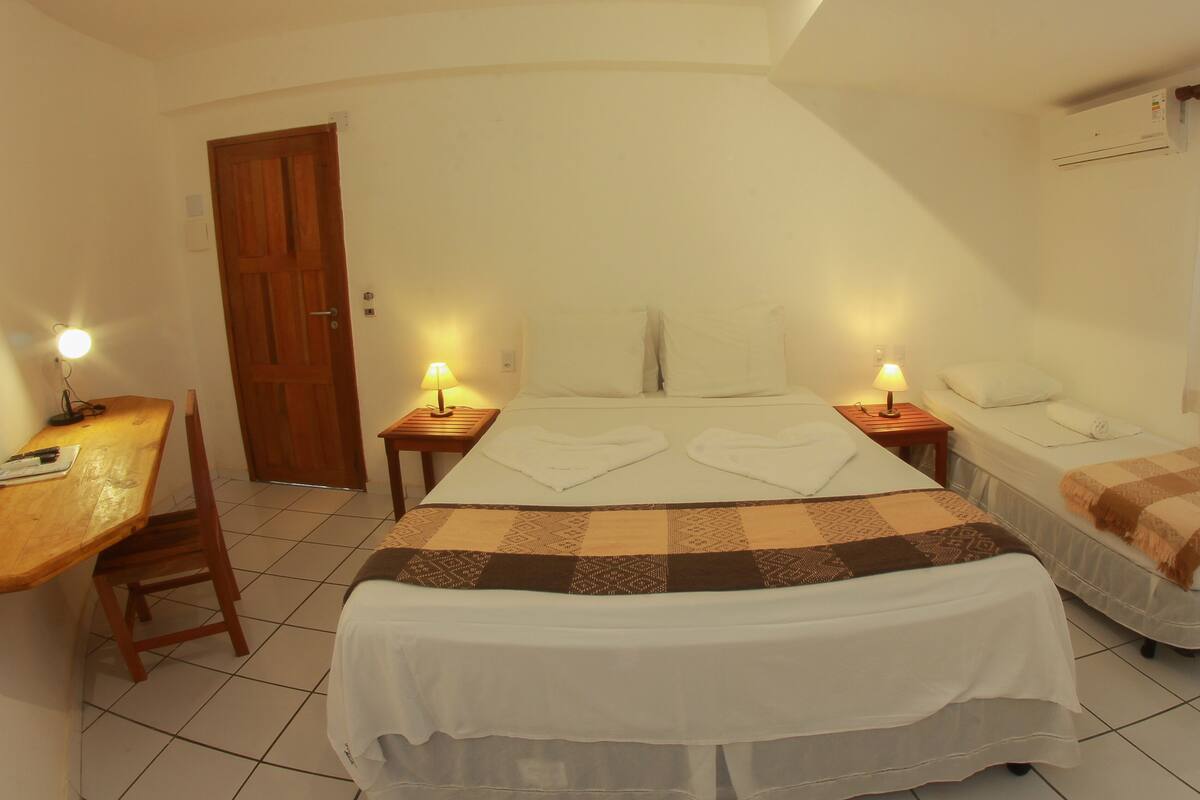A hotel room with a large bed, two bedside tables with lamps, a wooden desk, and a chair.