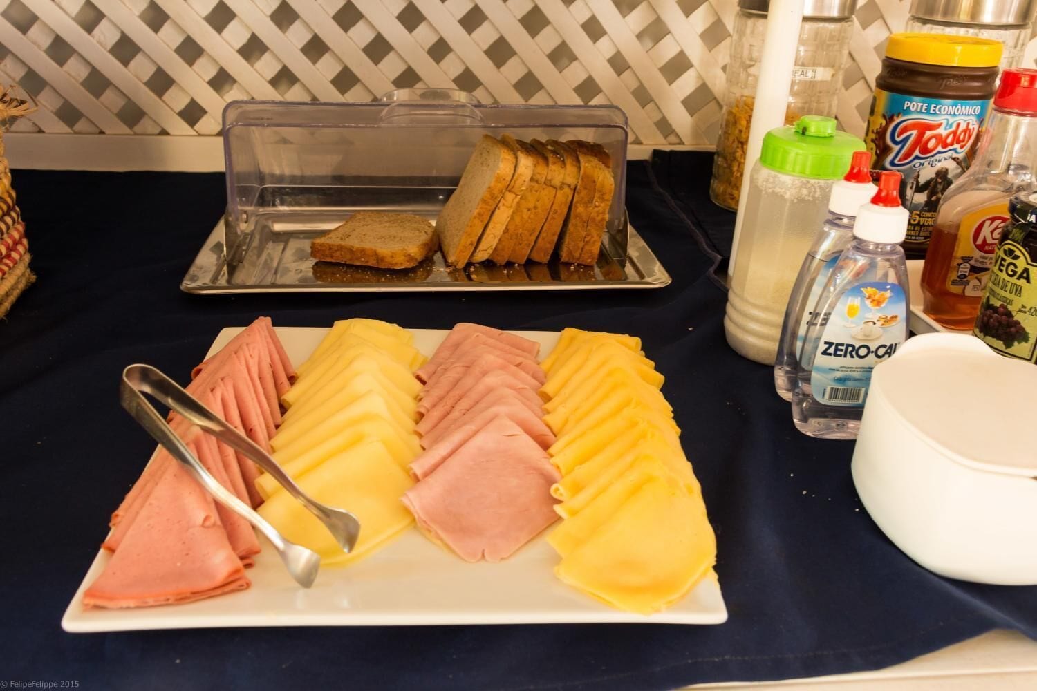 A breakfast buffet with sliced ham, cheese, and bread.