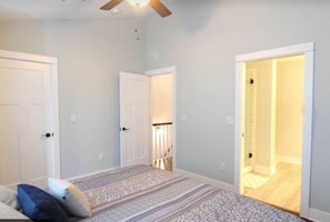 Cozy apartment with a large bed, ceiling fan, and two doors leading to additional space.