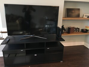 Relax in this stylish living room with a large flat-screen TV and ample storage.