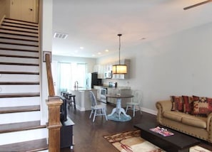 Staircase leads to an upper level, with a dining area, kitchen, and living space below.