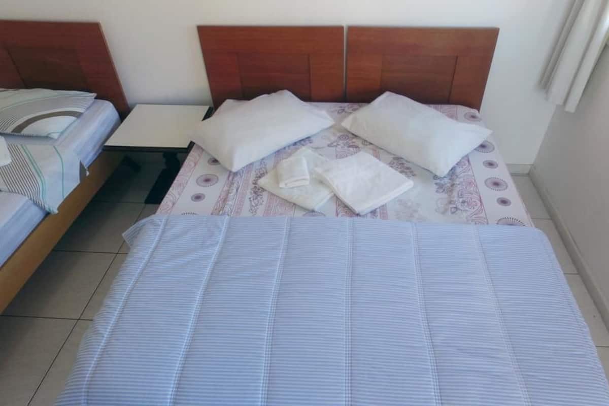 A hotel room with a bed, two bedside tables, and a window.