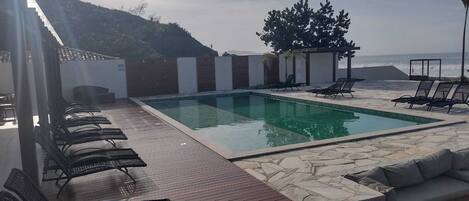 A pool area with lounge chairs and a stone deck.