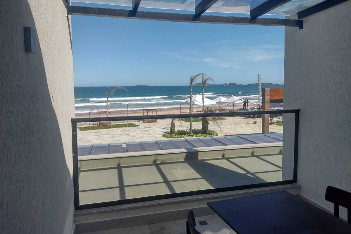 A balcony with a view of the beach, including umbrellas and a lifeguard tower.