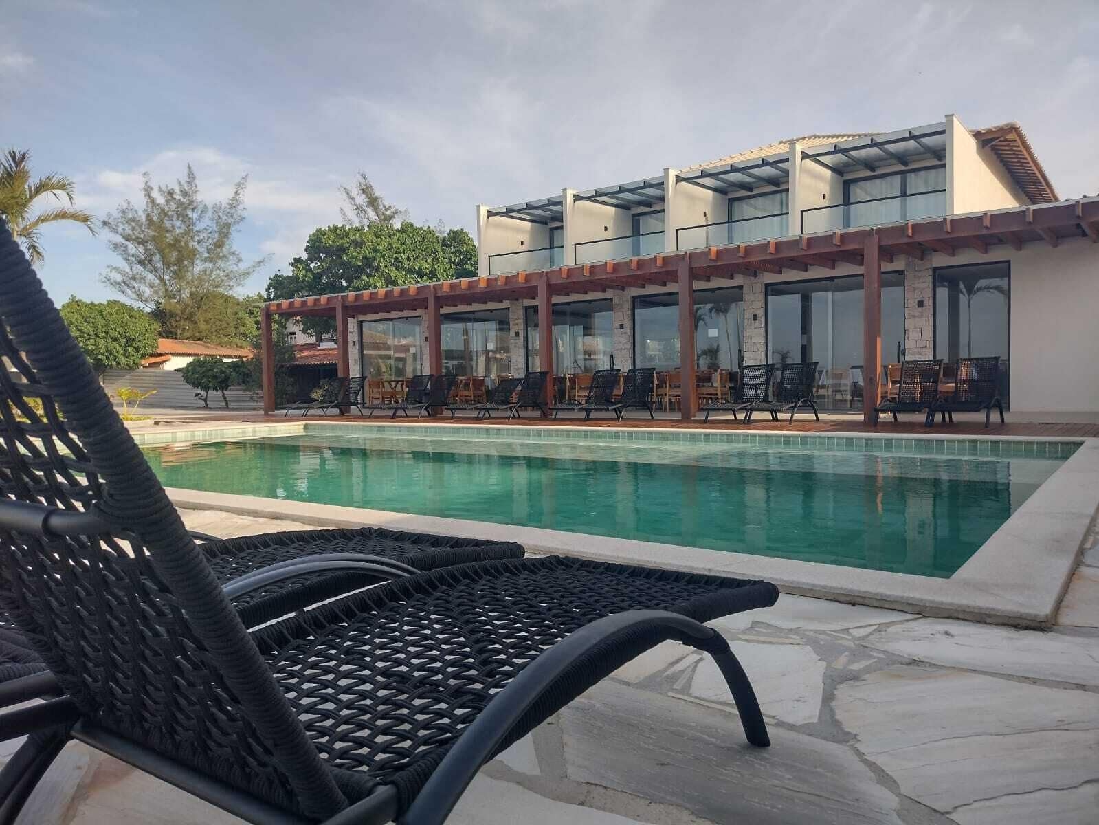 A pool area with lounge chairs and a building with large windows.