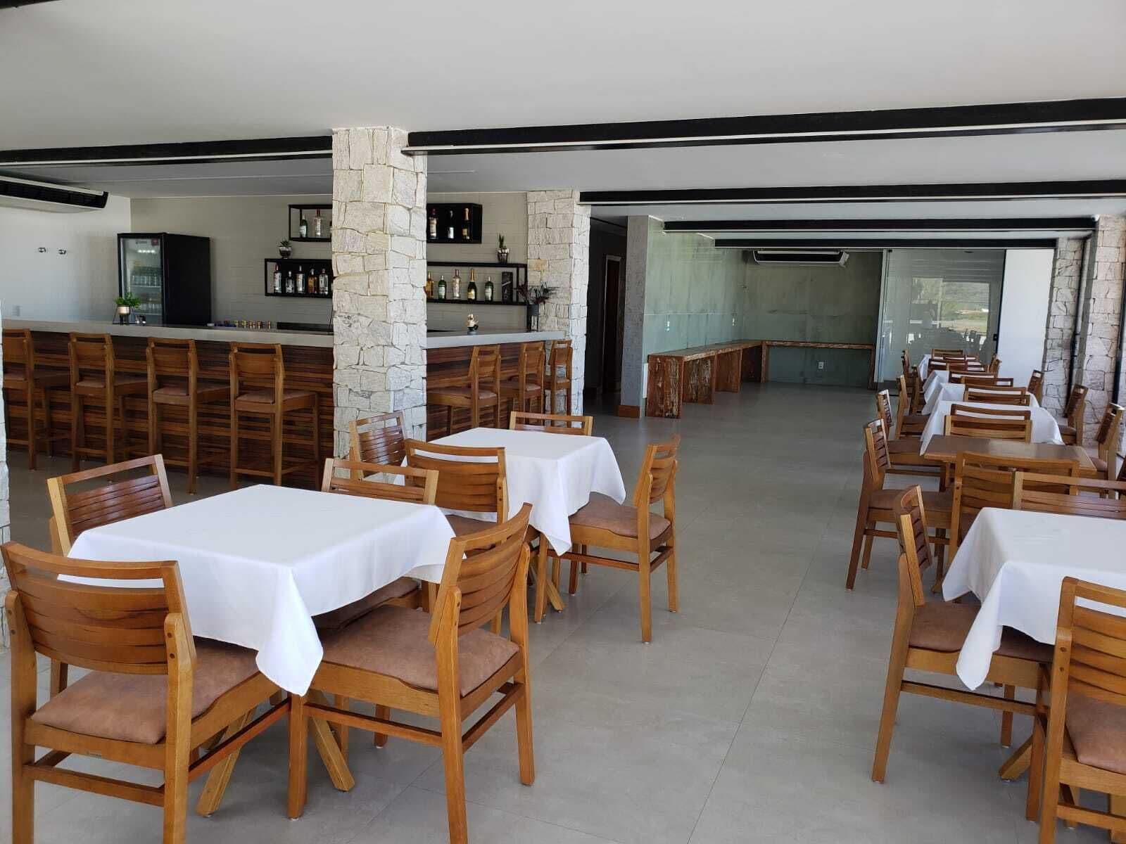 A restaurant with wooden tables and chairs, a bar area, and stone pillars.