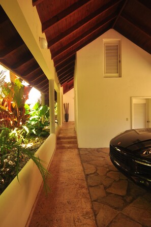 A covered walkway with a car parked on the right, leading to a door with a window.