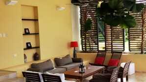 A spacious living area with a sofa set, a coffee table, and a dining table. There are two large woven pendant lights hanging from the ceiling. - Instyle Residences at Seahorse Ranch Villa 118 (Cabarete)