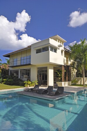 A modern two-story house with a swimming pool, outdoor seating, and a well-maintained garden. - Instyle Residences at Seahorse Ranch Villa 118 (Cabarete)