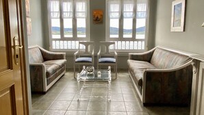 Una sala de estar con dos sofás, una mesa de centro de vidrio y dos sillones.