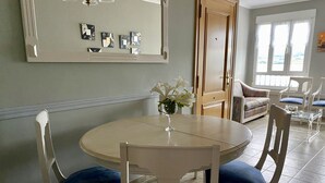 Un comedor con una mesa redonda y sillas, un florero con flores y un espejo en la pared.