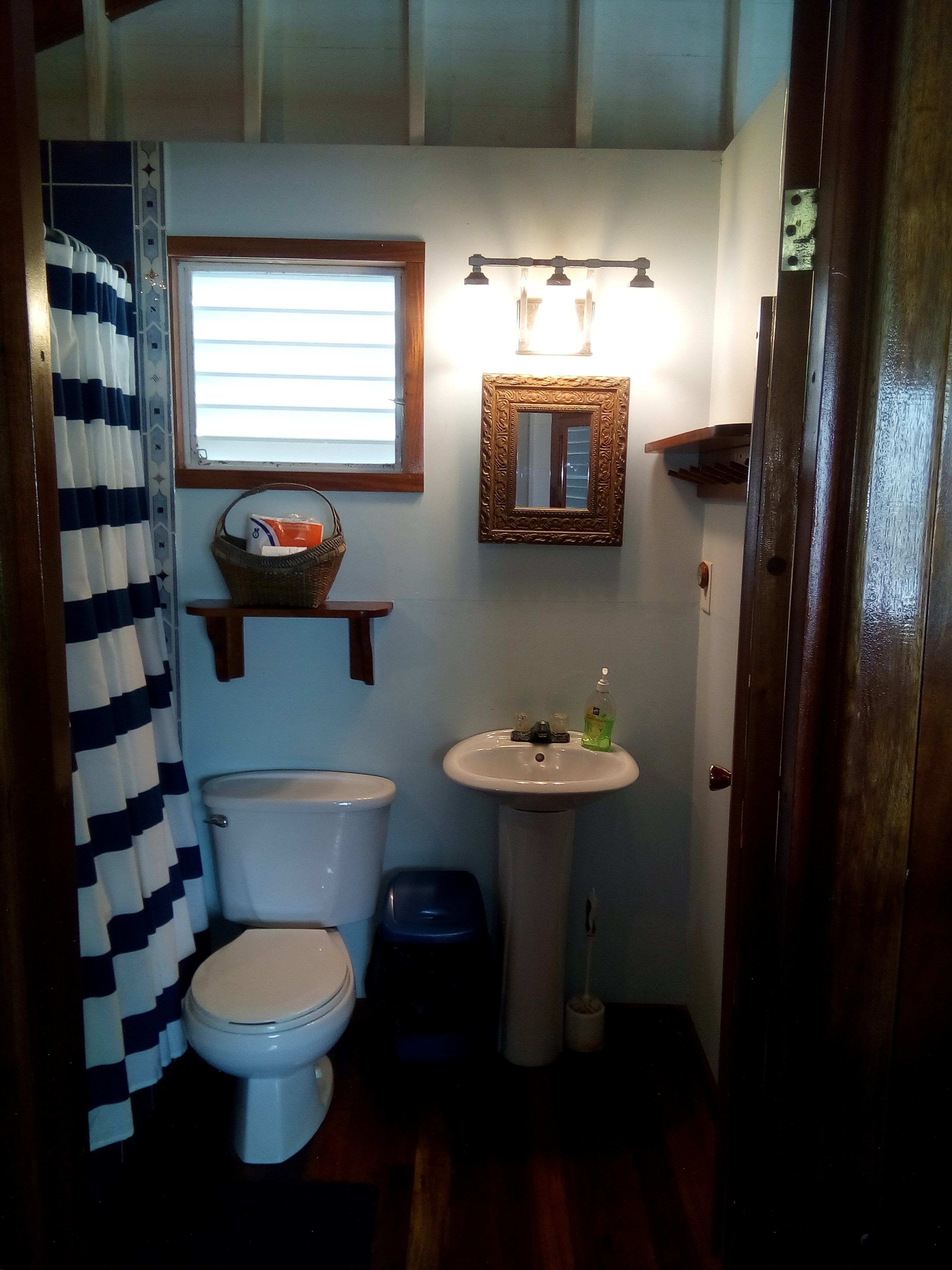 A compact bathroom with a toilet, sink, and a window with blinds.