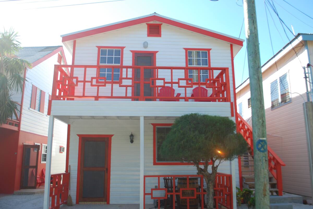 A two-story building with a balcony and a small tree in front.