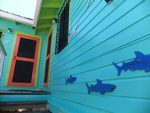 A turquoise house with red-framed windows and shark cutouts on the siding.