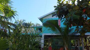 Un edificio de dos pisos con fachada azul y blanca, rodeado de follaje tropical.