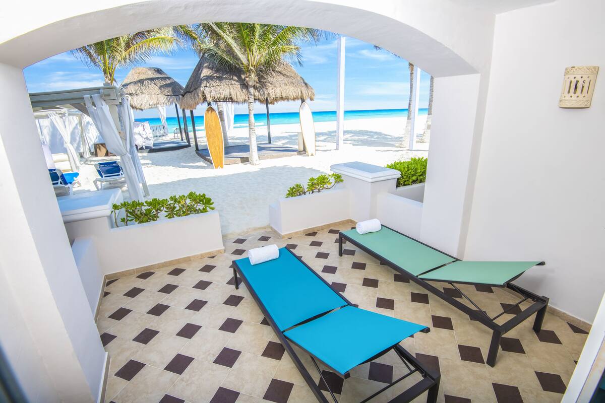 A beachside room with two reclining chairs, a small table, and a view of the beach and ocean.