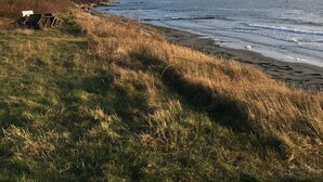 Un paysage côtier avec un premier plan herbeux, une côte rocheuse et un ciel dégagé.