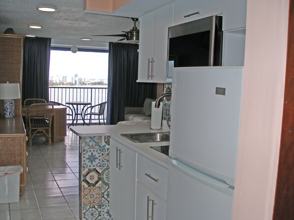 A kitchen with a balcony, a dining area with chairs, and a view of the city.