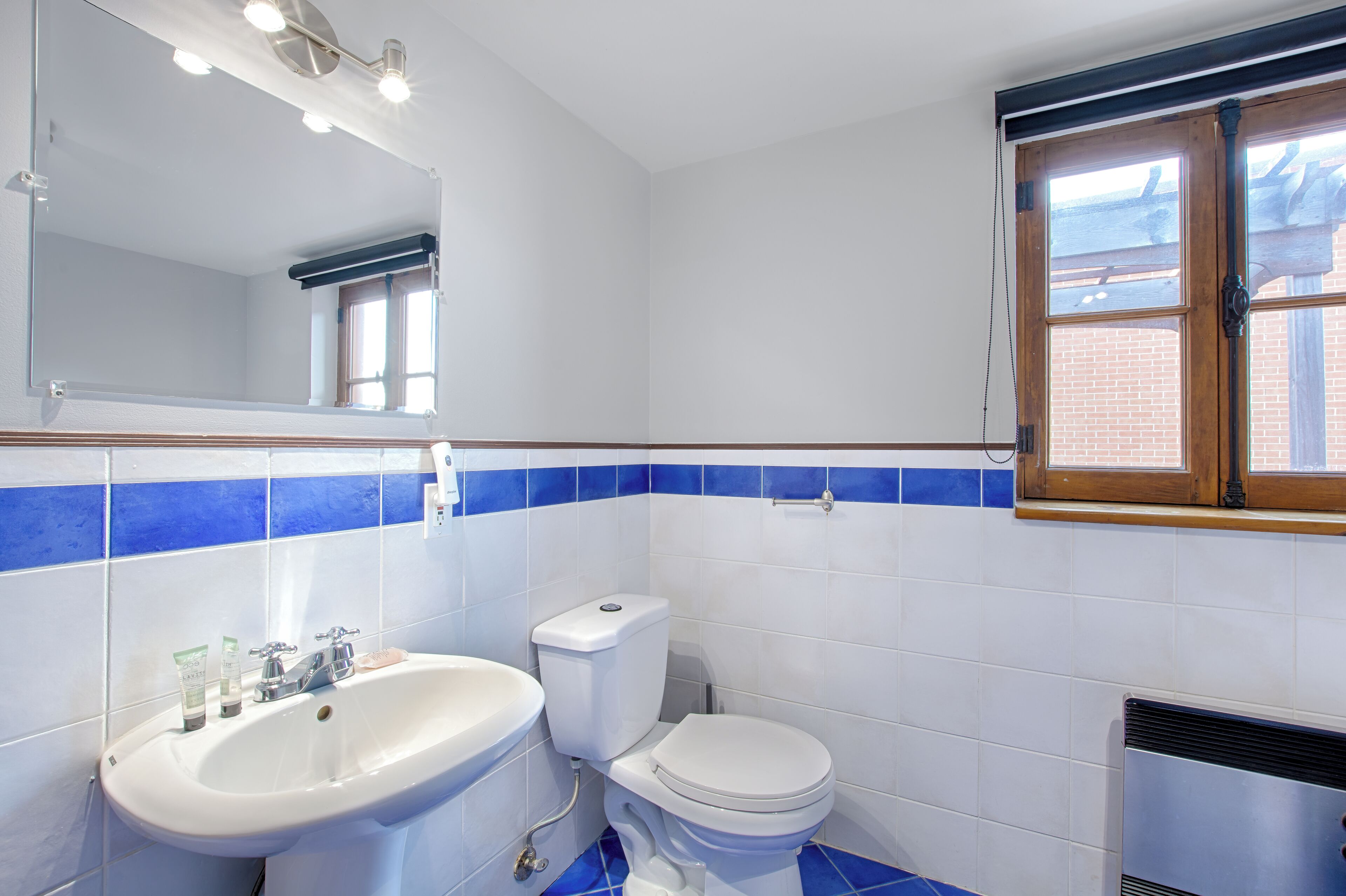Un baño con lavamanos blanco, inodoro y un espejo encima.