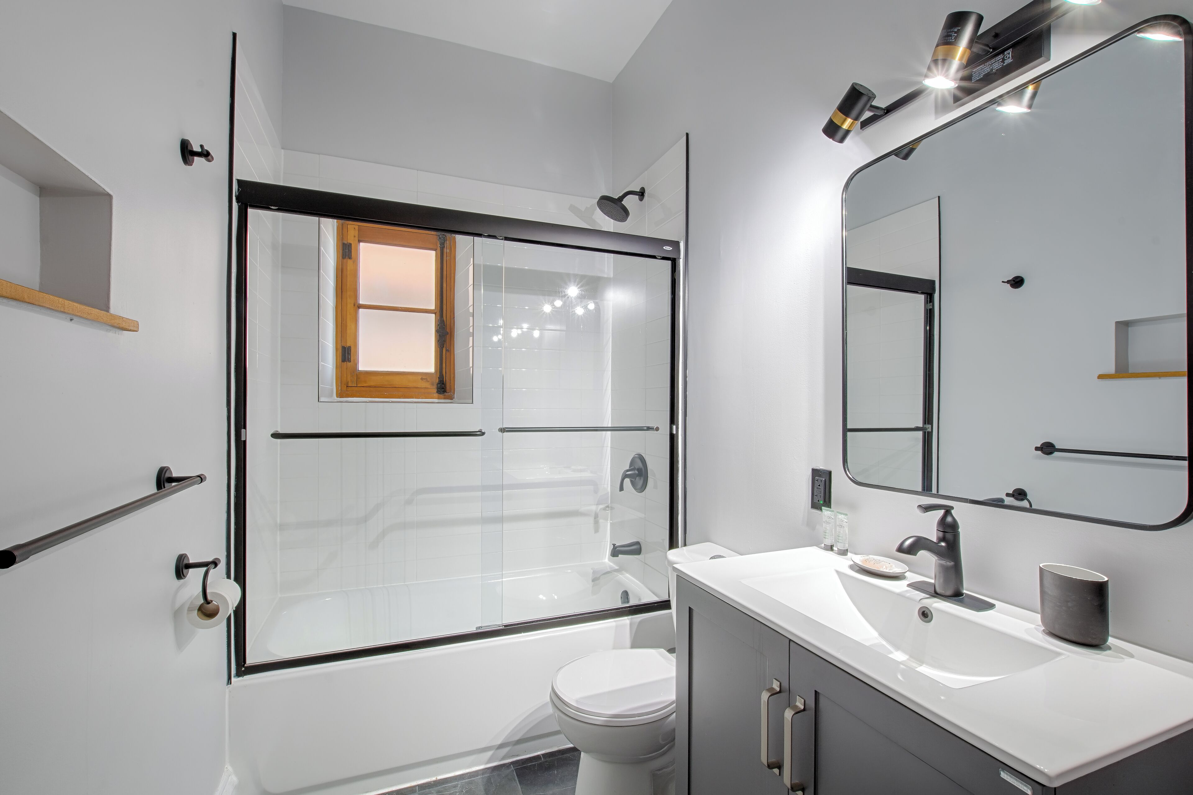 A modern bathroom with a glass-enclosed shower, a white sink, and a large mirror.