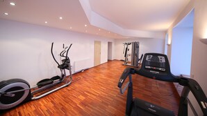Ein geräumiges Zimmer mit Holzboden, ausgestattet mit einem Crosstrainer und Laufband.