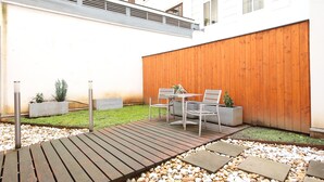 Eine Terrasse mit Holzdeck, Gartenmöbeln und einem Holenzaun.