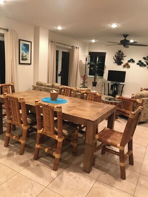 A dining area with a wooden table and chairs, a television, and a ceiling fan. - Happy Tarpon:  Boat Dock - Private Heated Pool - Fisherman and Family Fun! (Islamorada)