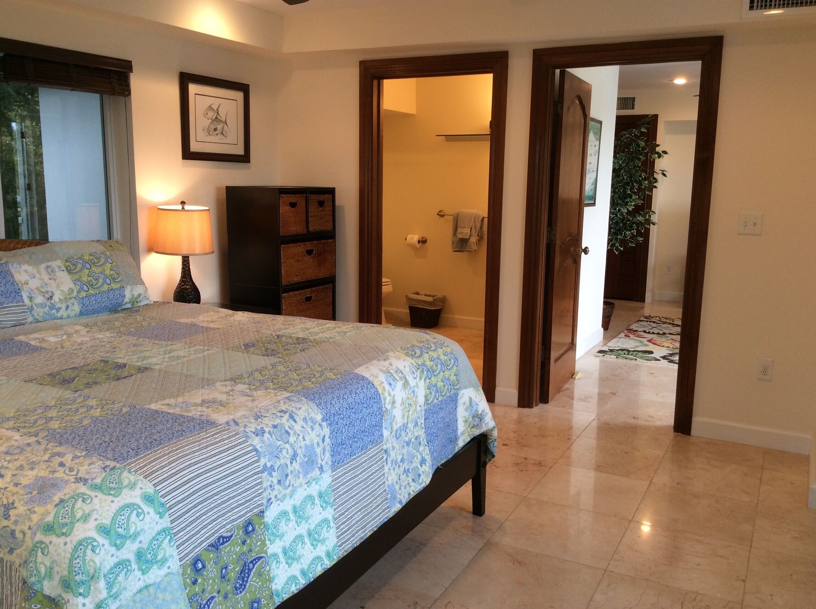 A bedroom with a large bed, a nightstand, a dresser, and a framed picture on the wall.