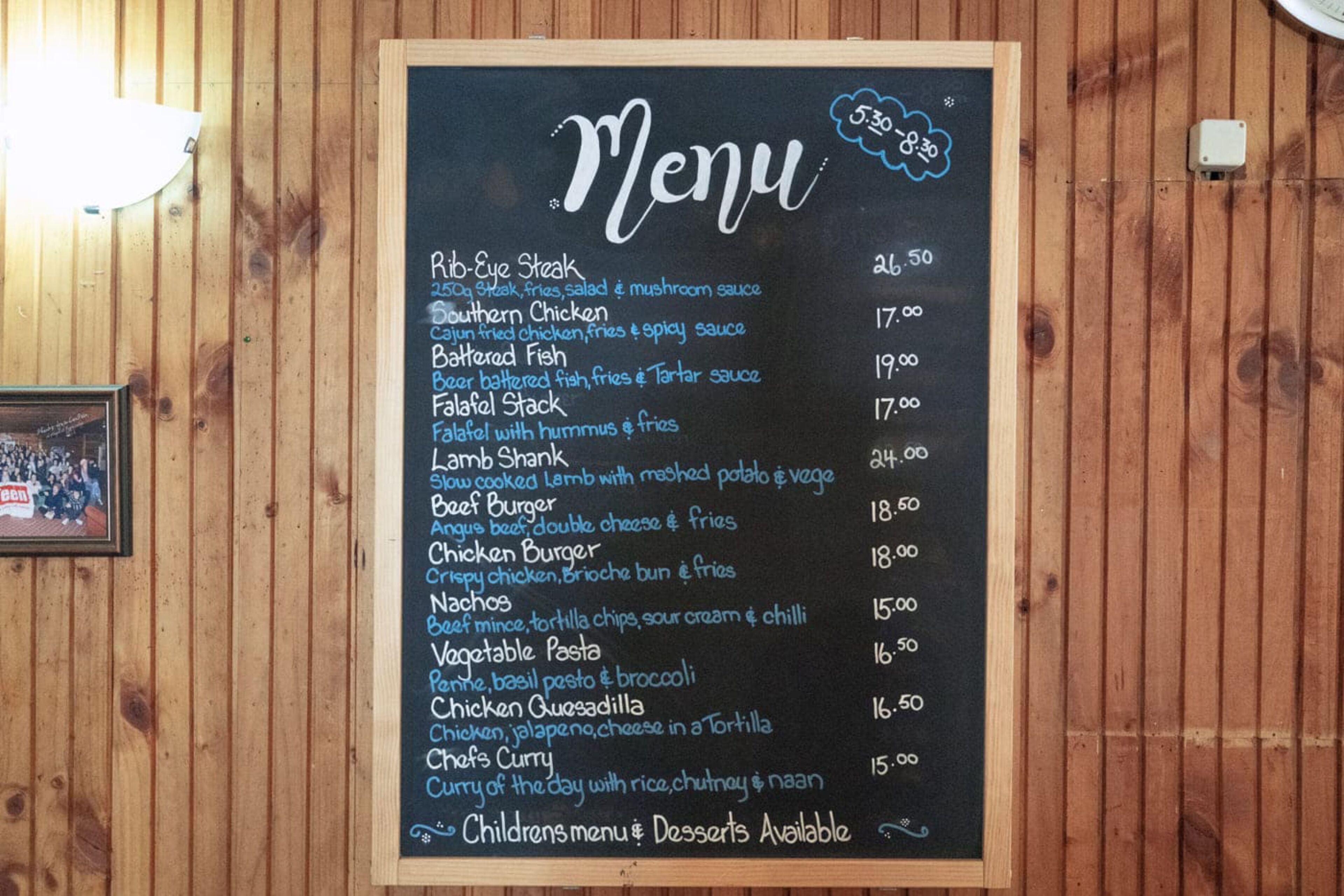 A chalkboard menu with various food items and prices.