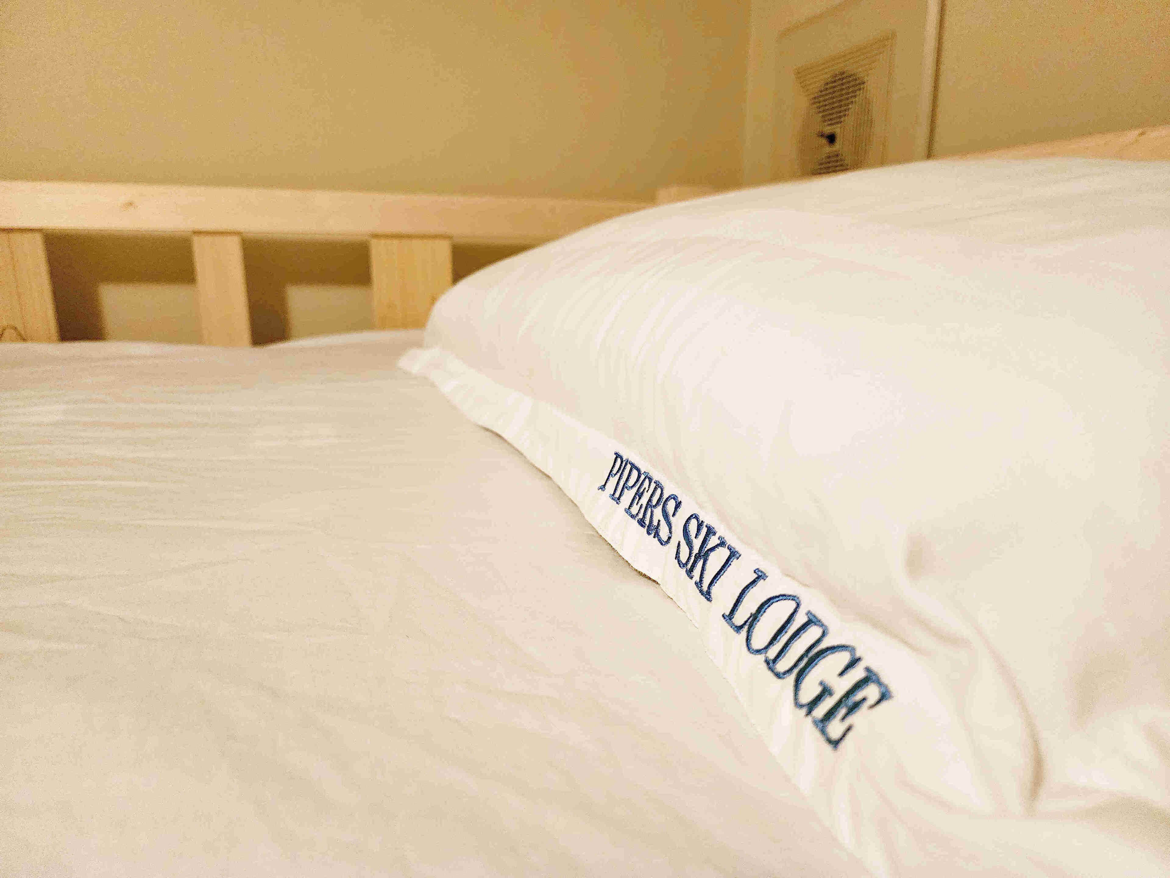 A bed with a pillow labeled "PIPERS SKI LODGE".