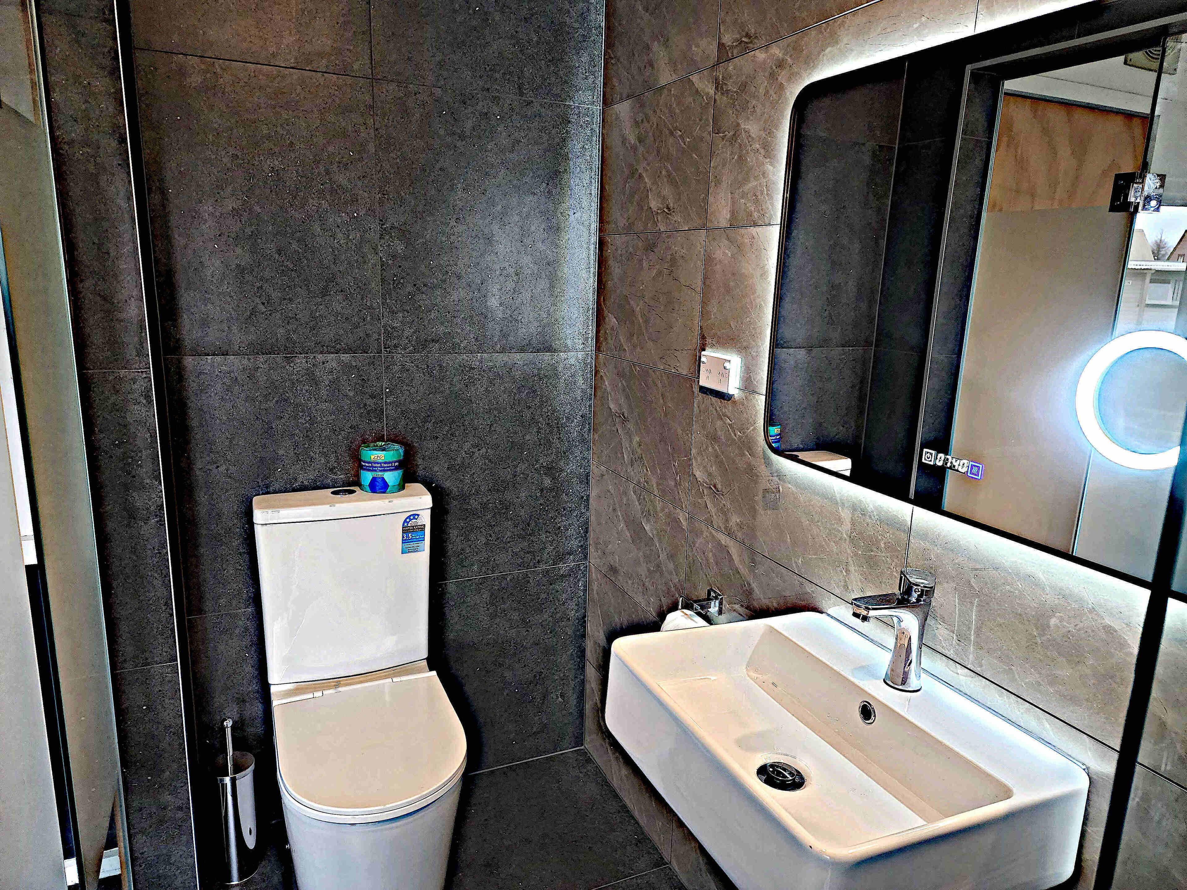 A modern bathroom with a toilet, sink, and mirror.