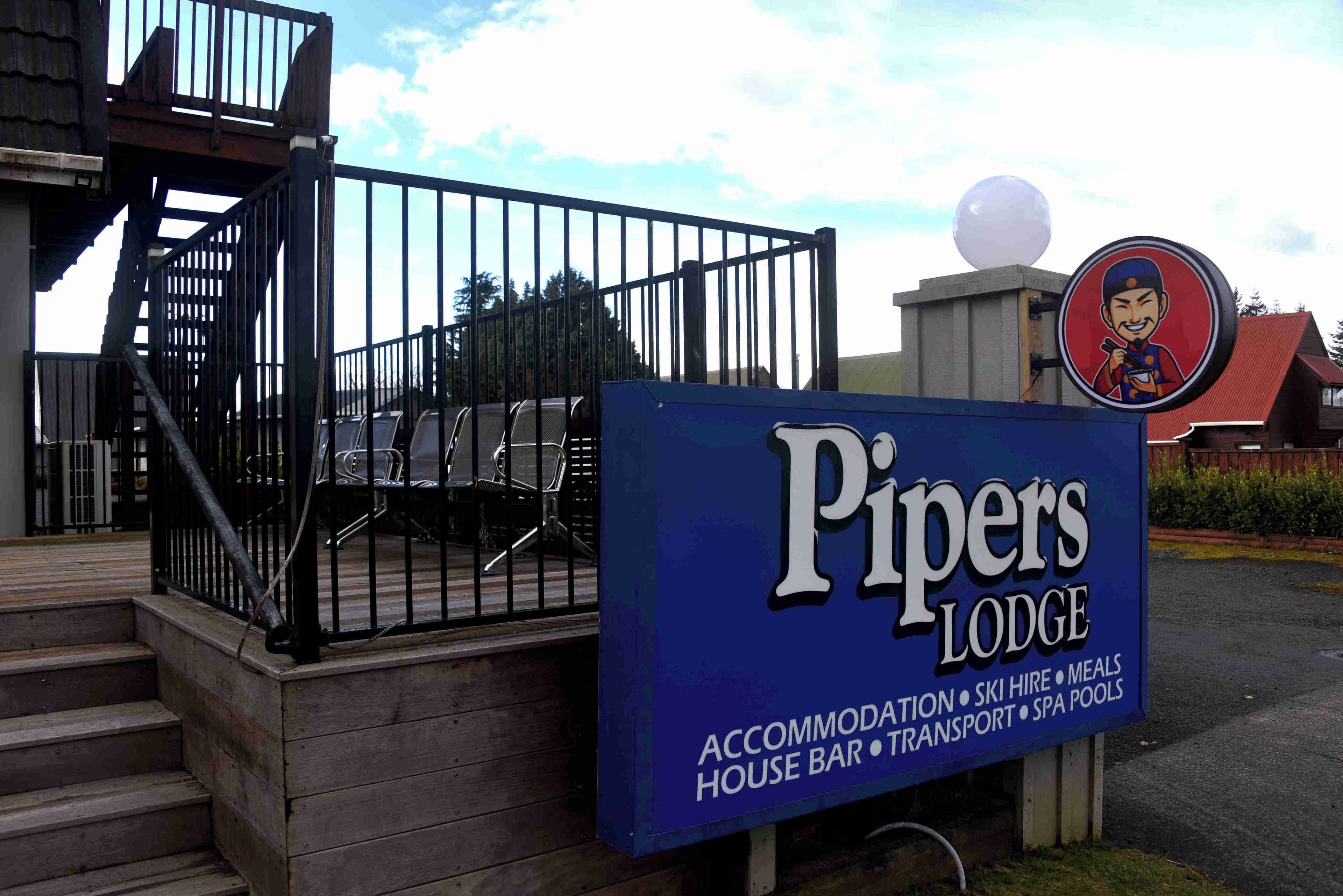 A sign for Pipers Lodge advertising accommodation, ski hire, meals, house bar, transport, and spa pools.