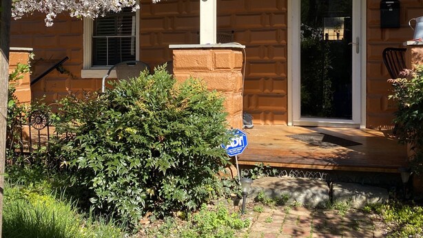 Une maison en briques avec une porte de garage, le numéro 73, et un porche doté d’un banc.
