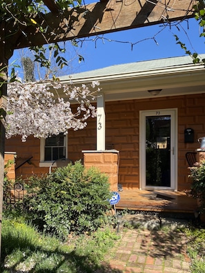 A brick house with a garage door, number 73, and a porch with a bench.