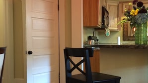 Une cuisine avec des meubles de rangement en bois, un plan de travail et une chaise.