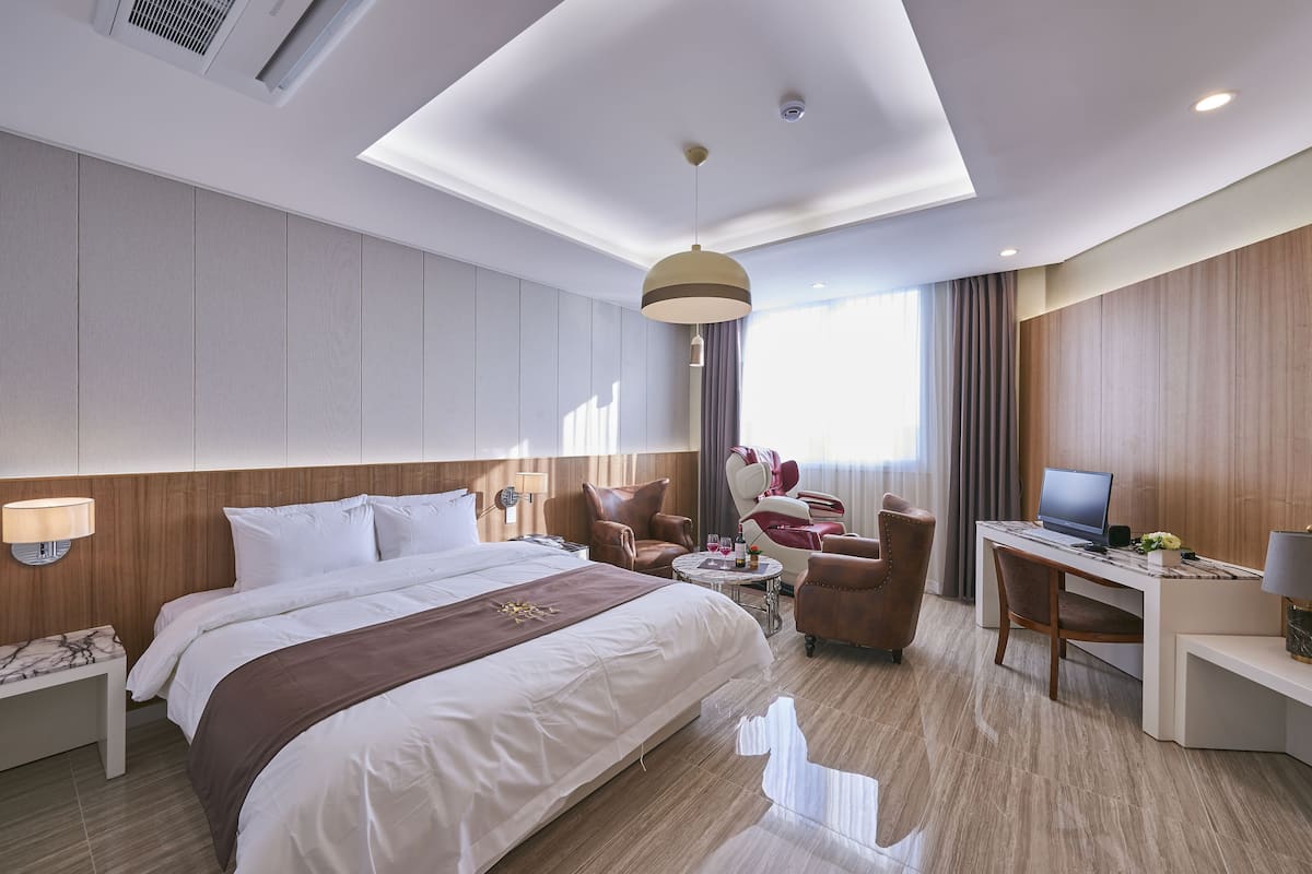 Ett modernt hotellrum med en stor säng, ett skrivbord, en stol och en soffa.