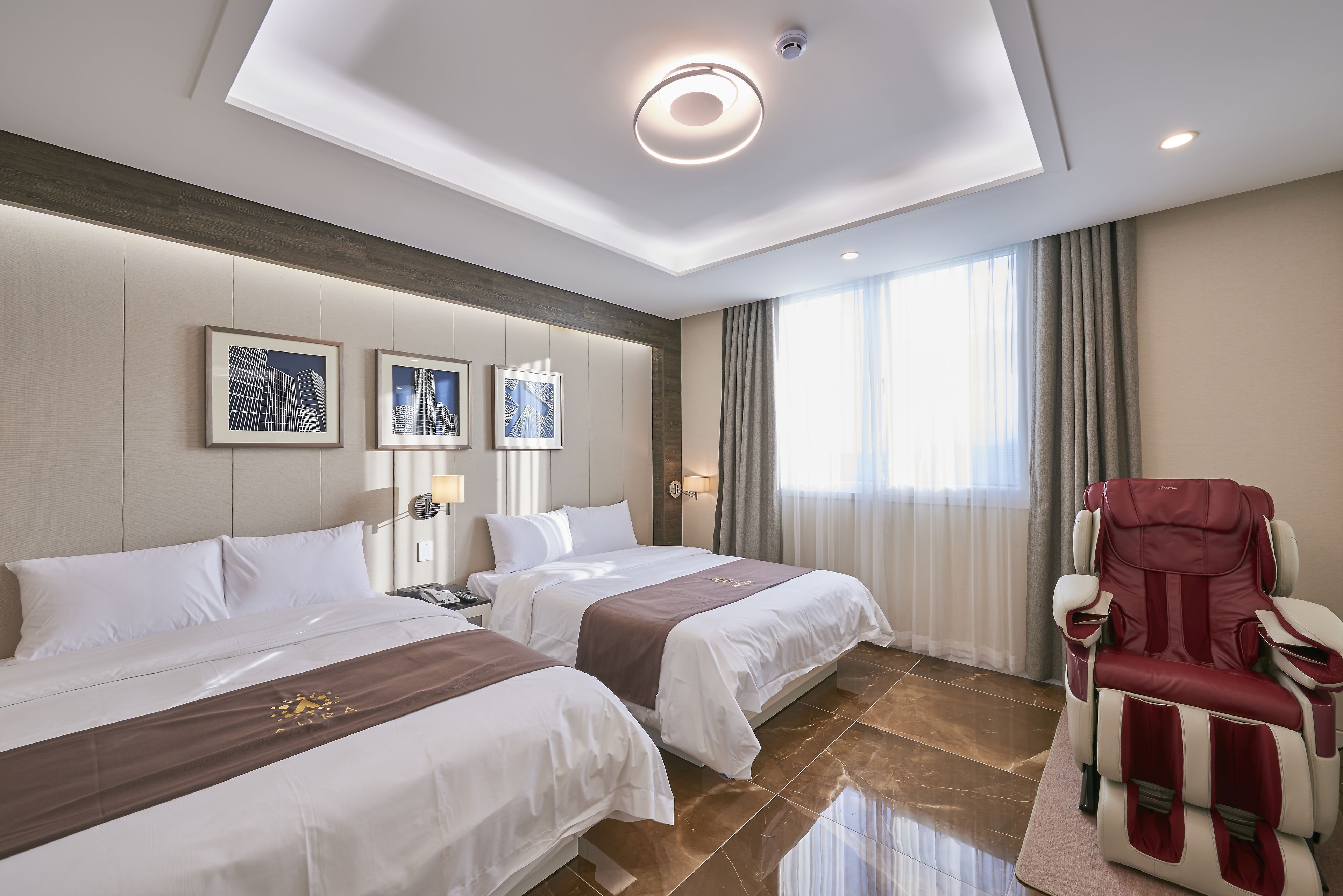 A hotel room with two beds, a massage chair, and artwork on the wall.