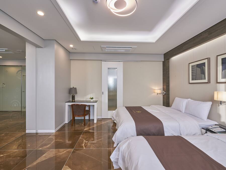 Una habitación de hotel moderna con dos camas, un escritorio y zona de ducha.