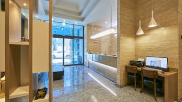 Um lobby moderno de hotel com uma mesa de recepção, um computador e uma área de estar.
