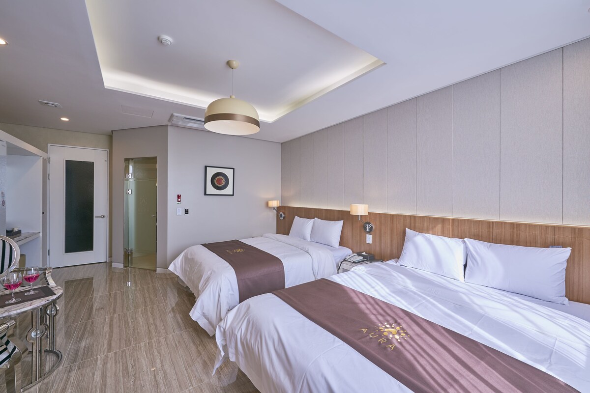 Ein Hotelzimmer mit zwei Betten, einem Schreibtisch mit Stuhl und einem Spiegel.