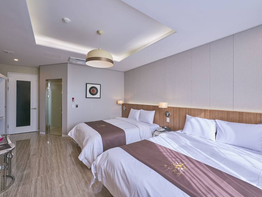 Habitación de hotel con dos camas, un escritorio con silla y un espejo.
